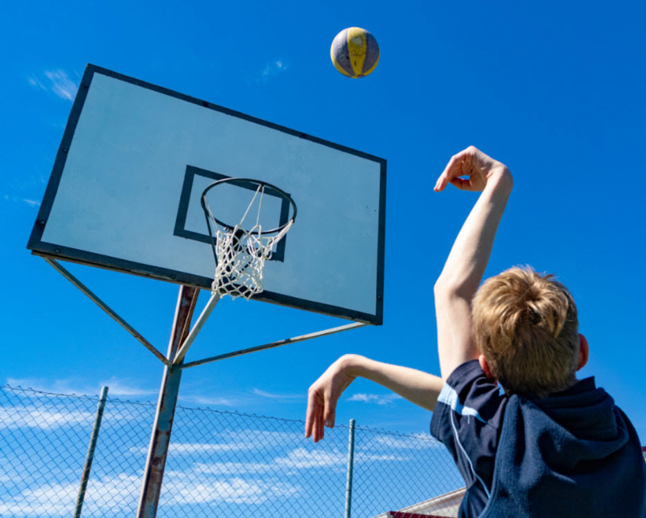 Boy shooting a ball at a basketball hoop